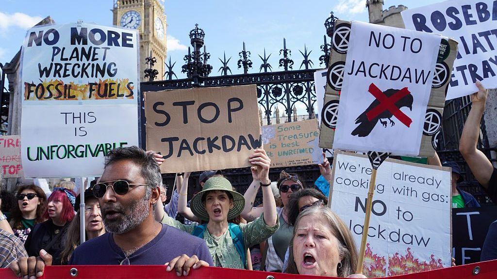 Protesters outside the Houses of Parliament hold up signs stating: "Stop Jackdaw", "No more planet wrecking fossil fuels this is unforgivable" and "No to Jackdaw".