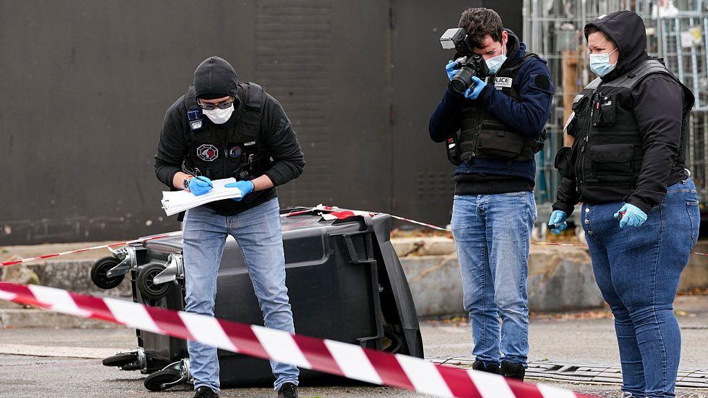 Police officers look at evidences on a site of a petrol station where a man opened fire from his car, killing one person and injuring four others according to police sources, in Trappes, Paris' suburb on October 23, 2026.