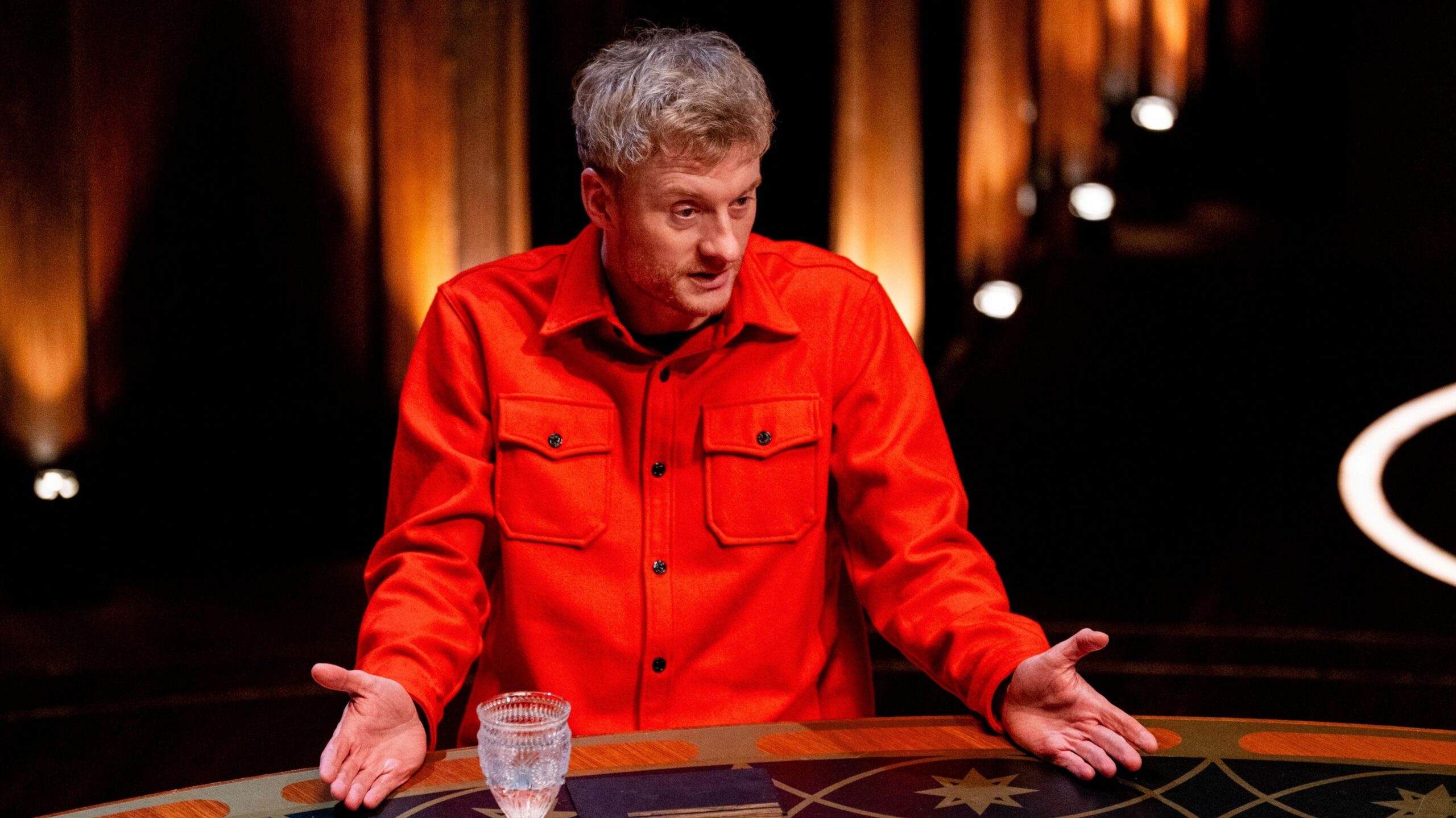 James Acaster speaking at the round table with both palms outstretched