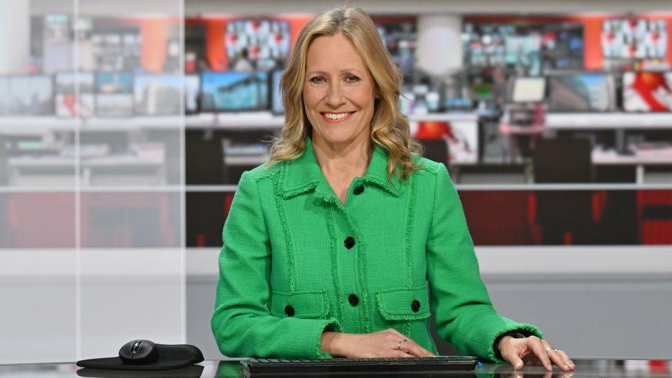 Sophie Raworth presenting in the BBC News studio, wearing a green jacket