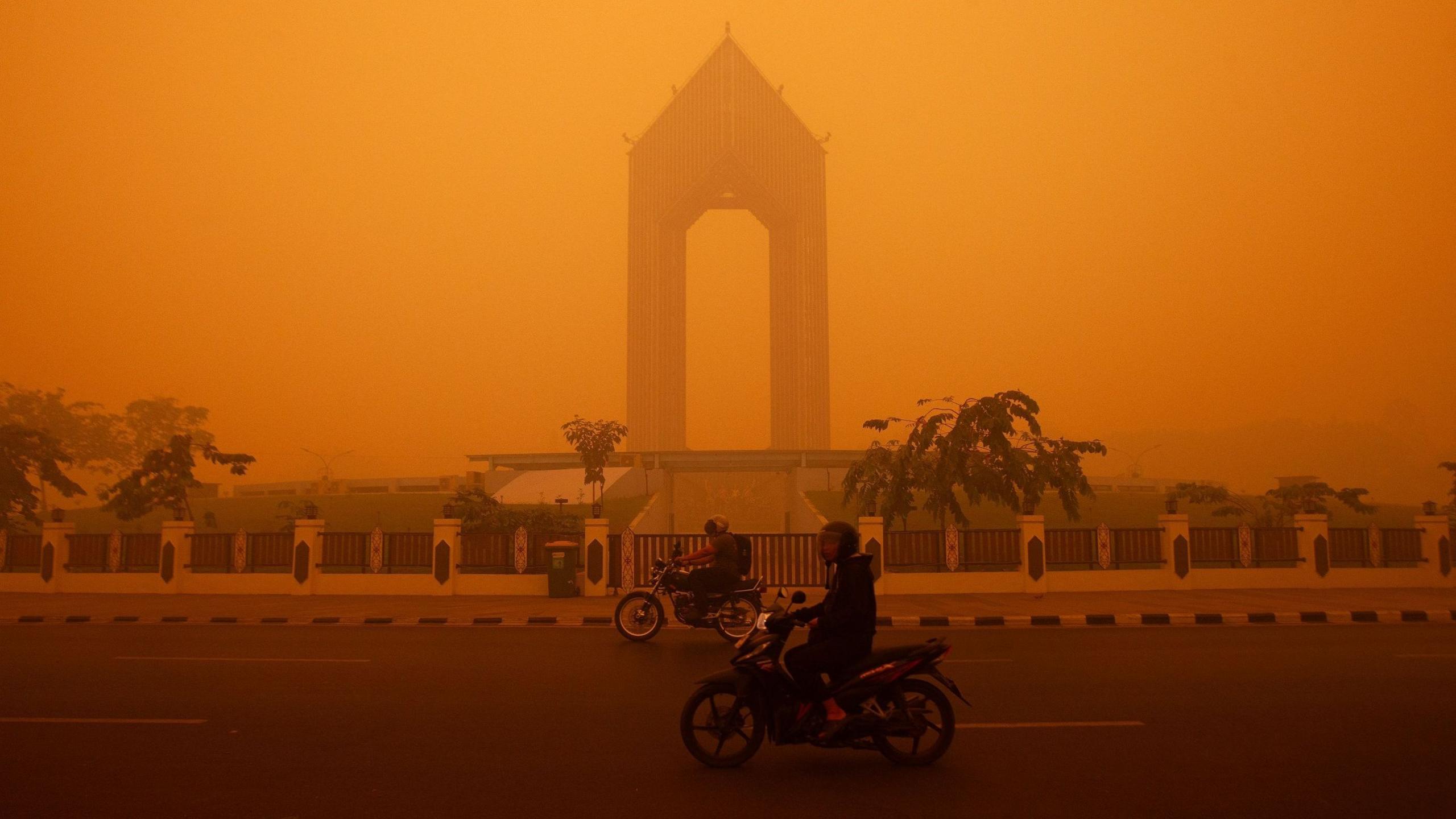 Motorcyclists ride in the morning in Palangkaraya, Central Kalimantan amid thick haze from forest and land fires in the region