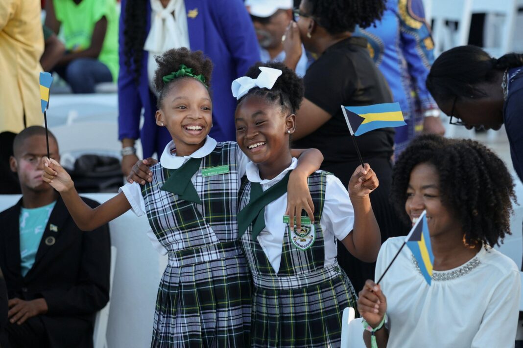 King acknowledges ‘suffering of the past’ as Caribbean tour begins Primary students smile and hold flags of the Bahamas ahead of a youth rally with Britain's King Charles at Clifford Park