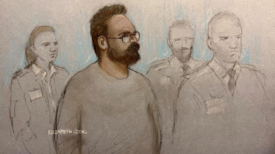 Widdecombe suspect in court charged with preparing terrorist acts against Farage A court sketch of Joshua Kerry, surrounded by three guards. He has a beard and wears glasses.