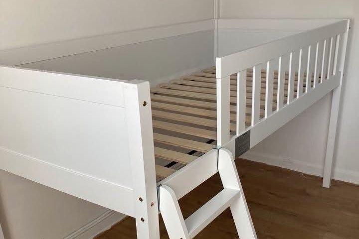 A white wooden bed with slats on either side.