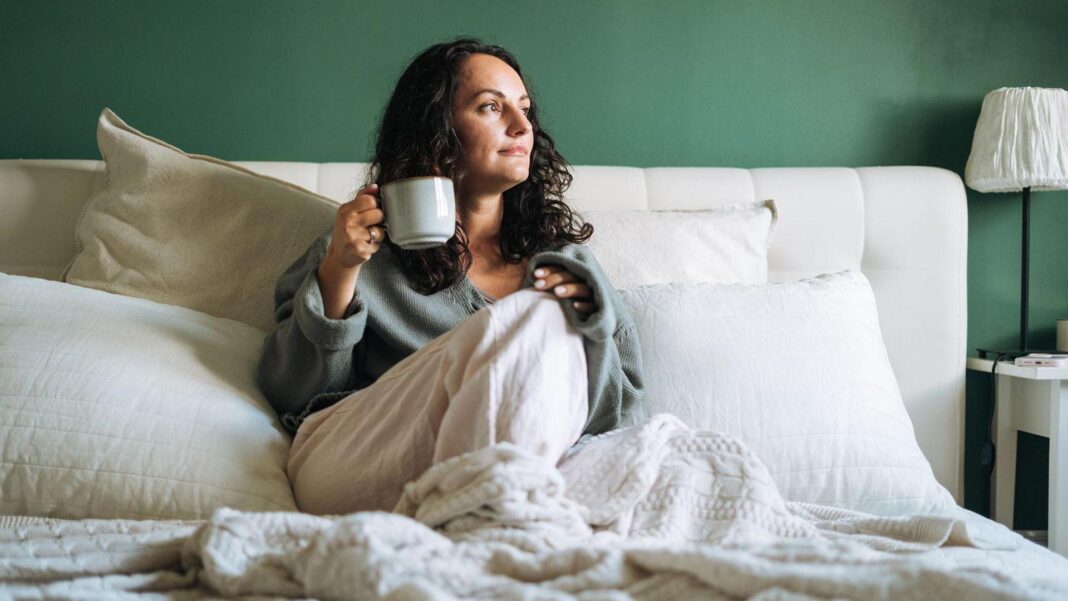 Is ‘ferritin face’ a real thing – and can you really spot low iron from looks? A woman in bed drinking a cup of tea