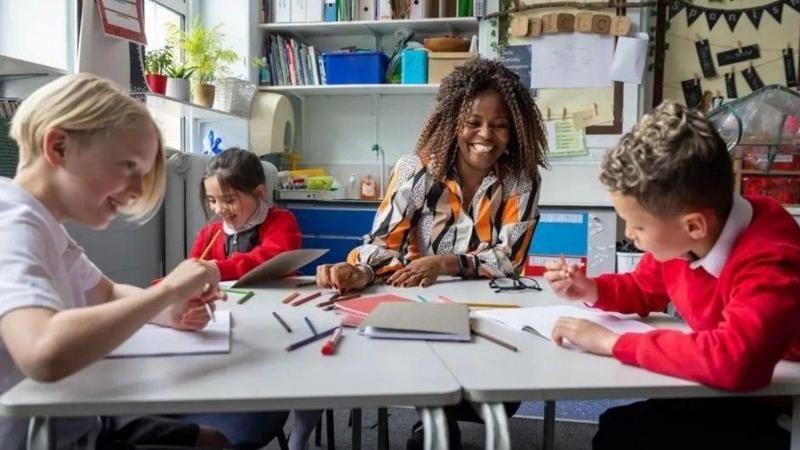 A group of children with a teacher sat at a table in a school.