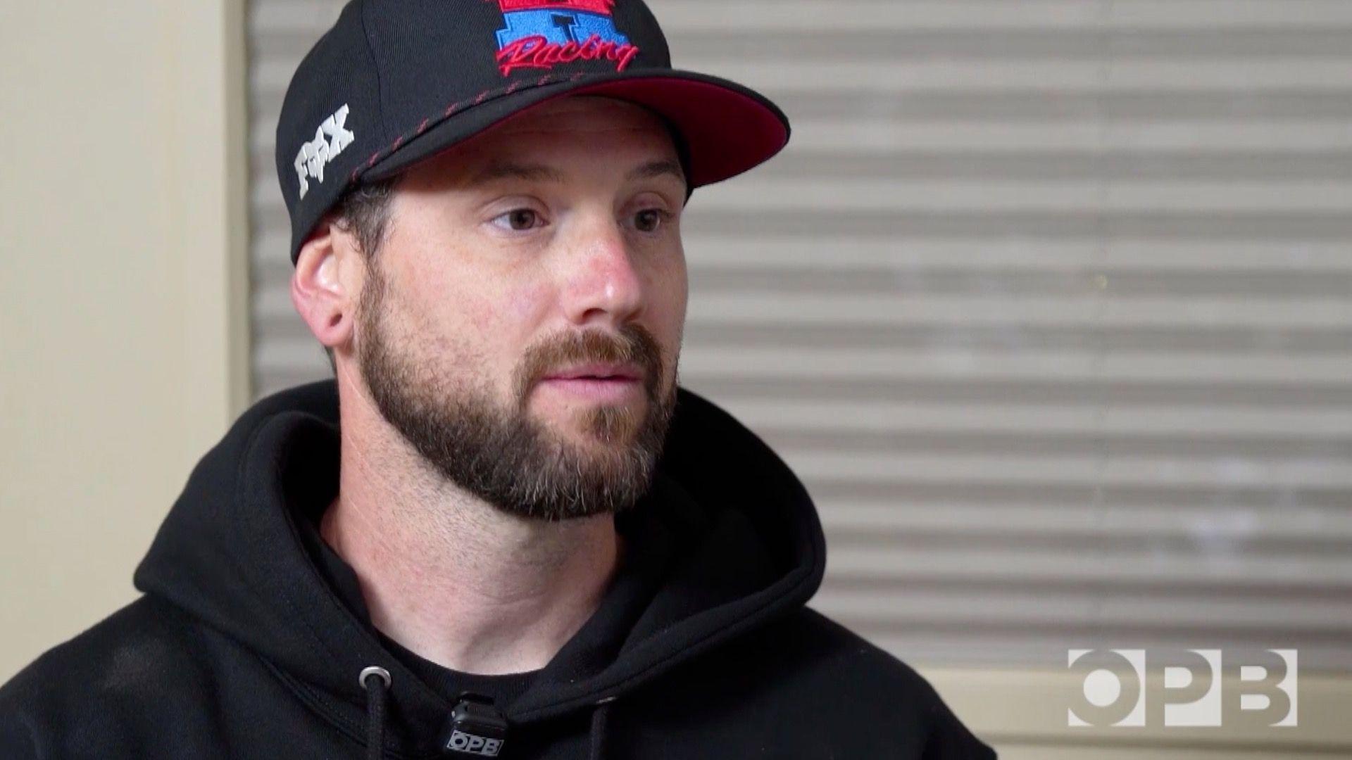 A man wears a black hat and a black hooded sweatshirt