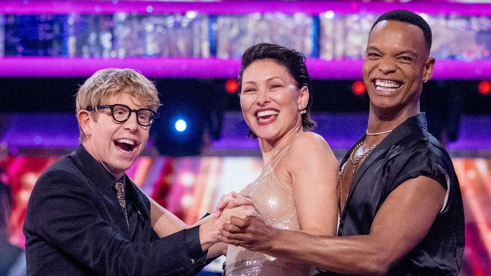 Josh Widdicombe, Emma Willis and Johannes Radebe smiling and standing together in a three-way dance hold