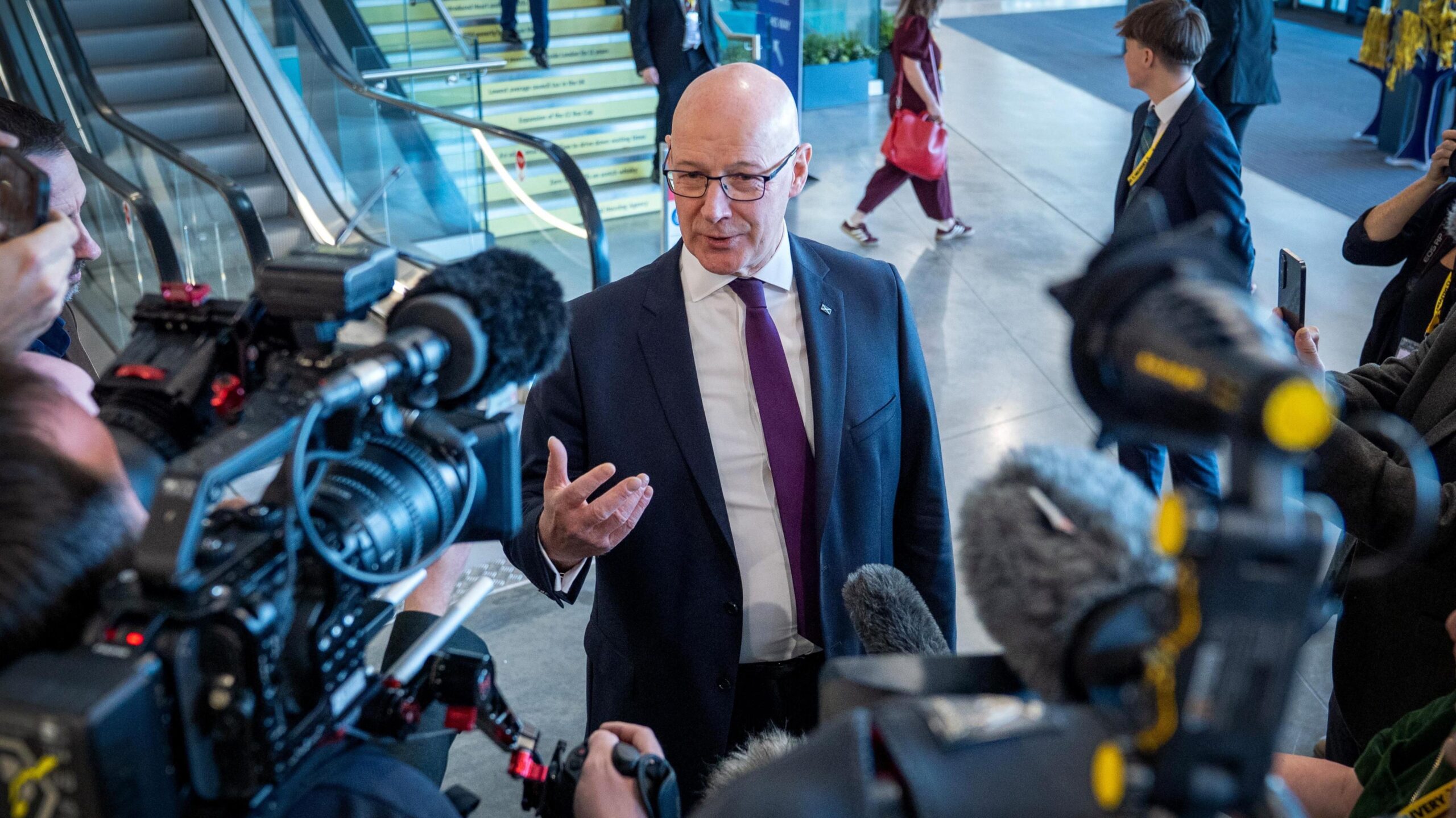 John Swinney standing in front of a number of reporters holding cameras and microphones at the SNP conference in Aberdeen.