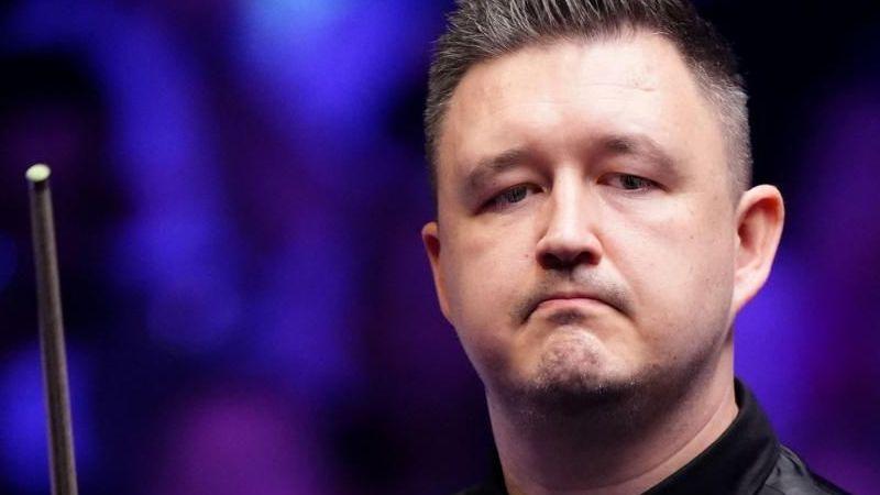 Kyren Wilson looking off camera holding a snooker cue.