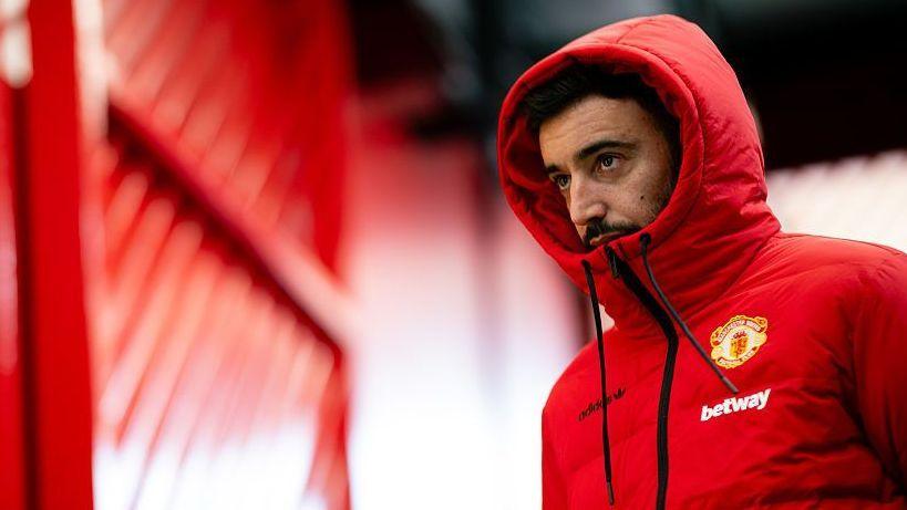 Bruno Fernandes wearing a red Manchester United coat