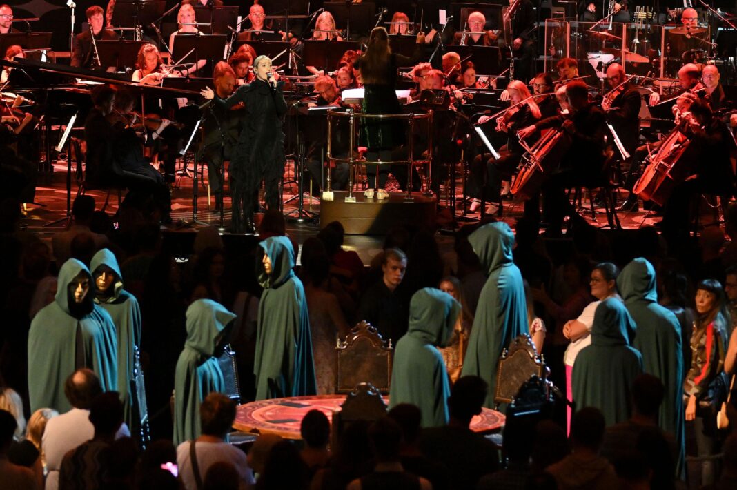 Cloaked figures surround the famous Traitors' round table, while an orchestra plays in the background