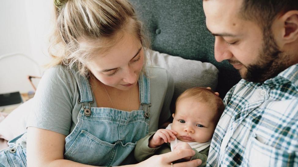 A young woman and a man with a baby in the middle of them.
