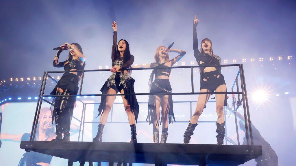 Blackpink stand on a raised platform while performing in concert