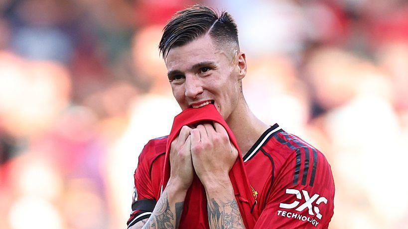 Benjamin Sesko pulling the bottom of his red shirt towards his mouth