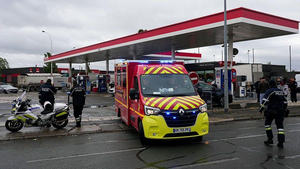 Firefighters intervene on a site of a petrol station where a man opened fire from his car, killing one person and injuring four others according to police sources, in Trappes, Paris' suburb on October 23, 2026.