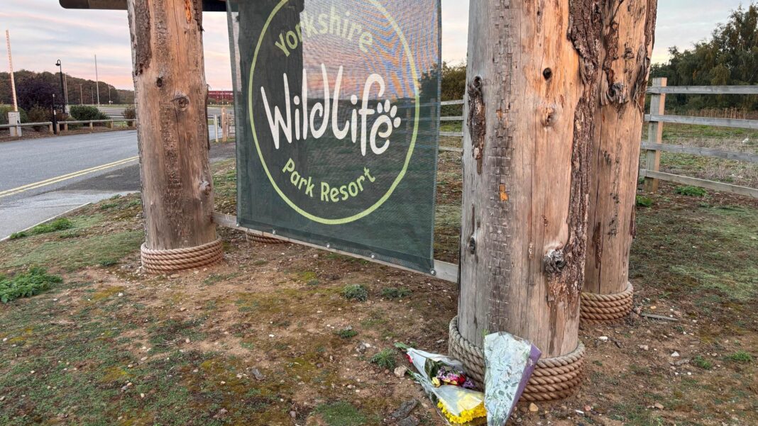 Flowers below a green sign hung between two wooden posts. On the sign it says: Yorkshire Wildlife Park Resort.
