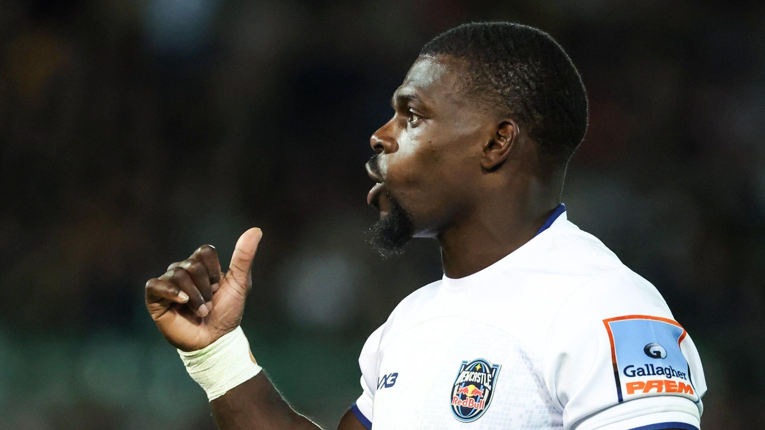 Christian Wade gives a thumbs up on his right hand during Newcastle's game with Northampton. He is wearing a white kit.