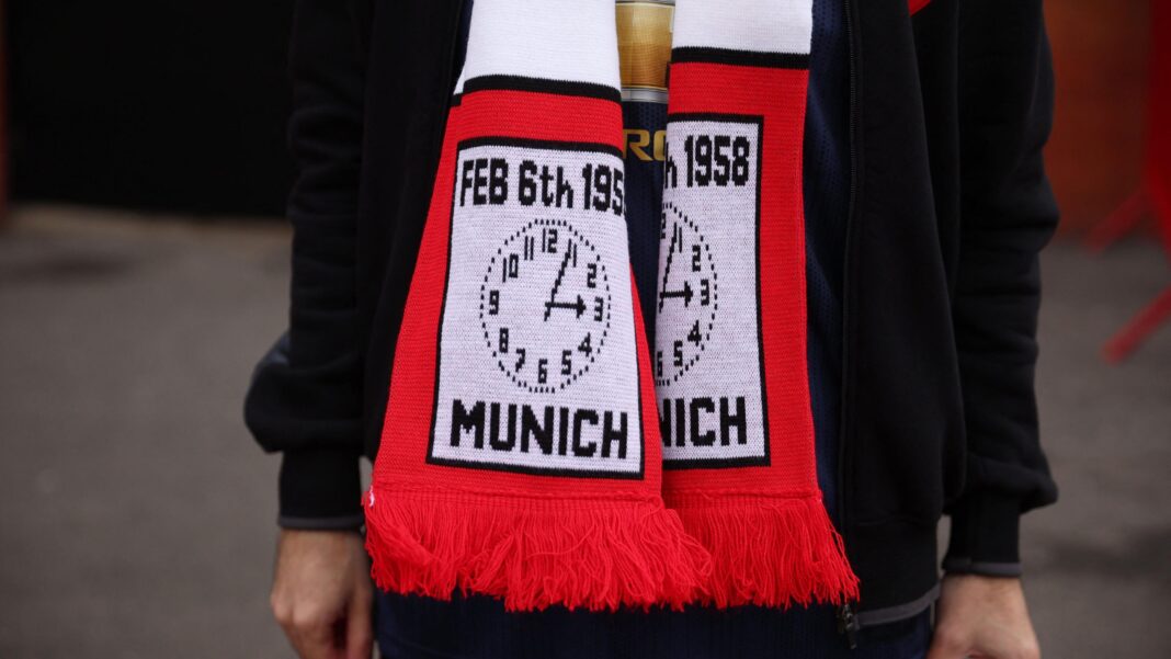 A close-up of a young person, shown from the shoulders to the upper legs, wearing a red, white and black commemorative scarf. There is an illustration of a clock face and the word 