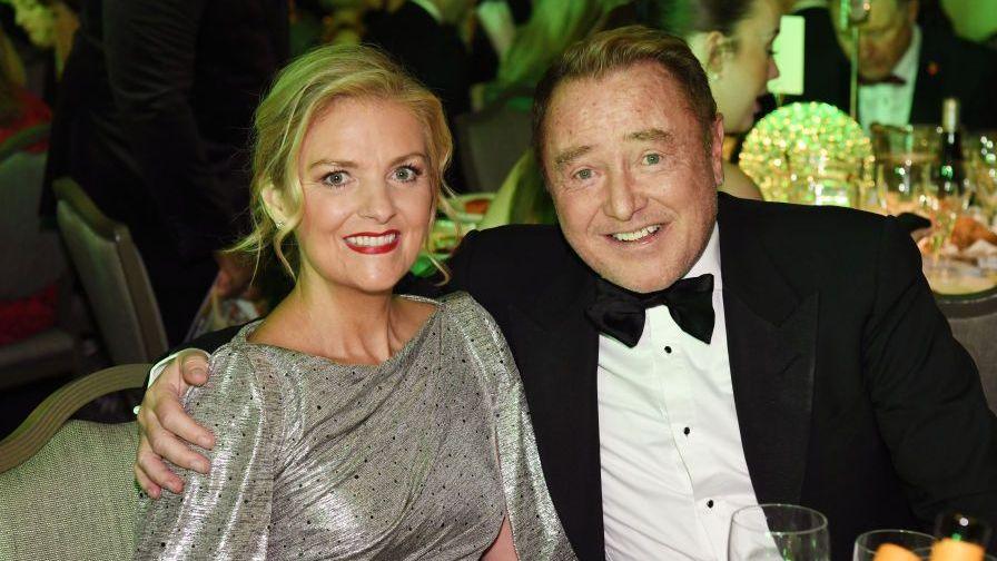 Niamh O'Brien and Michael Flatley attend The Irish Post Awards in 2024. Niamh has long, blonde hair, tied back and wears a silver dress. Michael has short, ginger hair and wears a black tuxedo.
