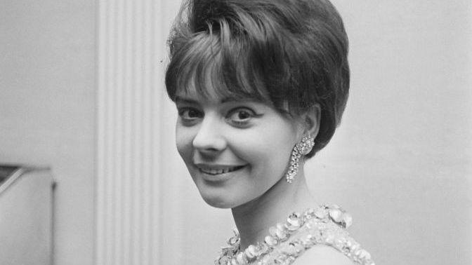Lena Martell pictured in the 1960s in black and white. She has short hair and is wearing large earring and an embellished dress.