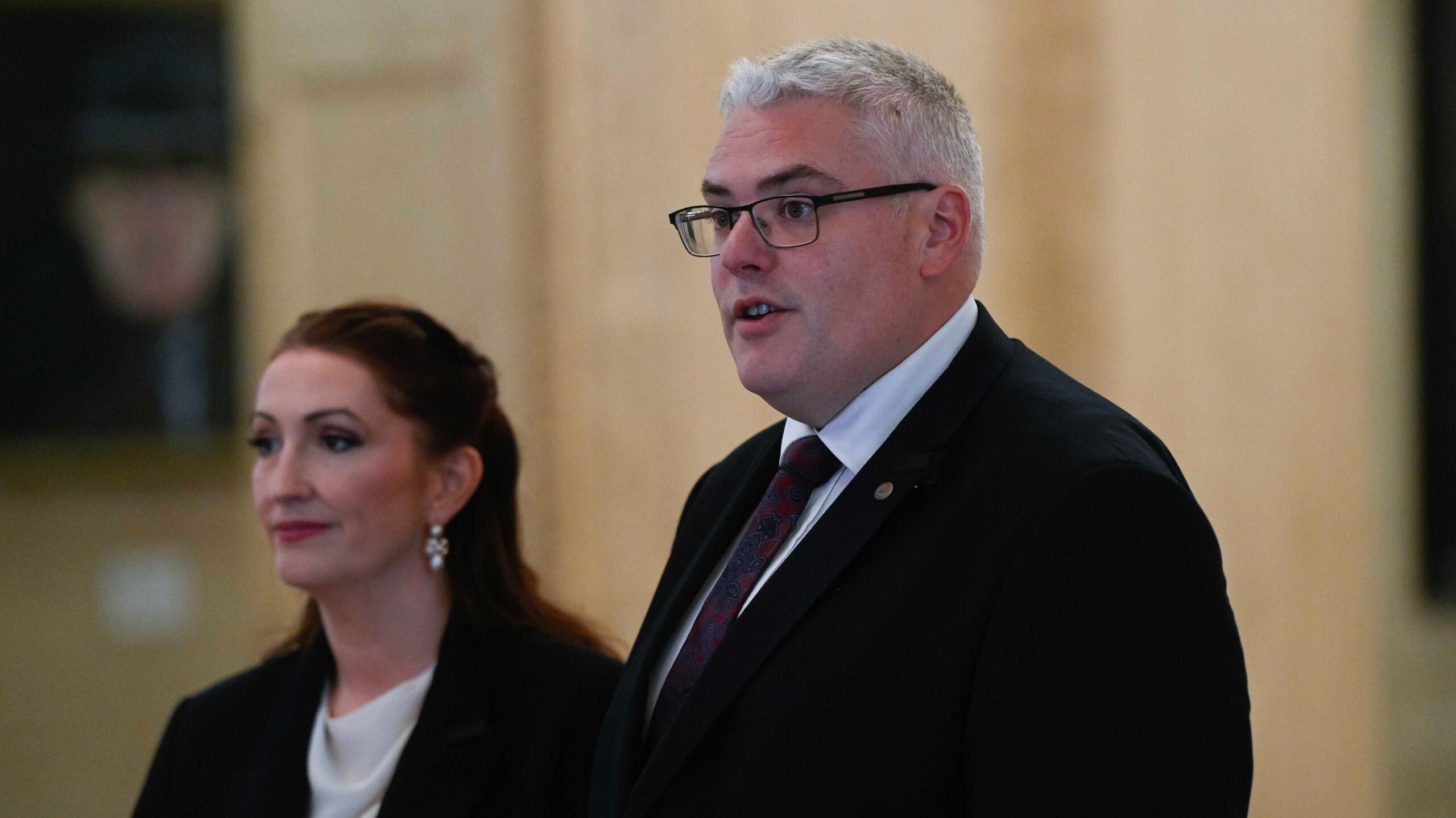 Emma Little-Pengelly with brown hair, dark blazer and white blouse standing beside Gavin Robinson who has grey hair, glasses, dark blazer, tie and white shirt