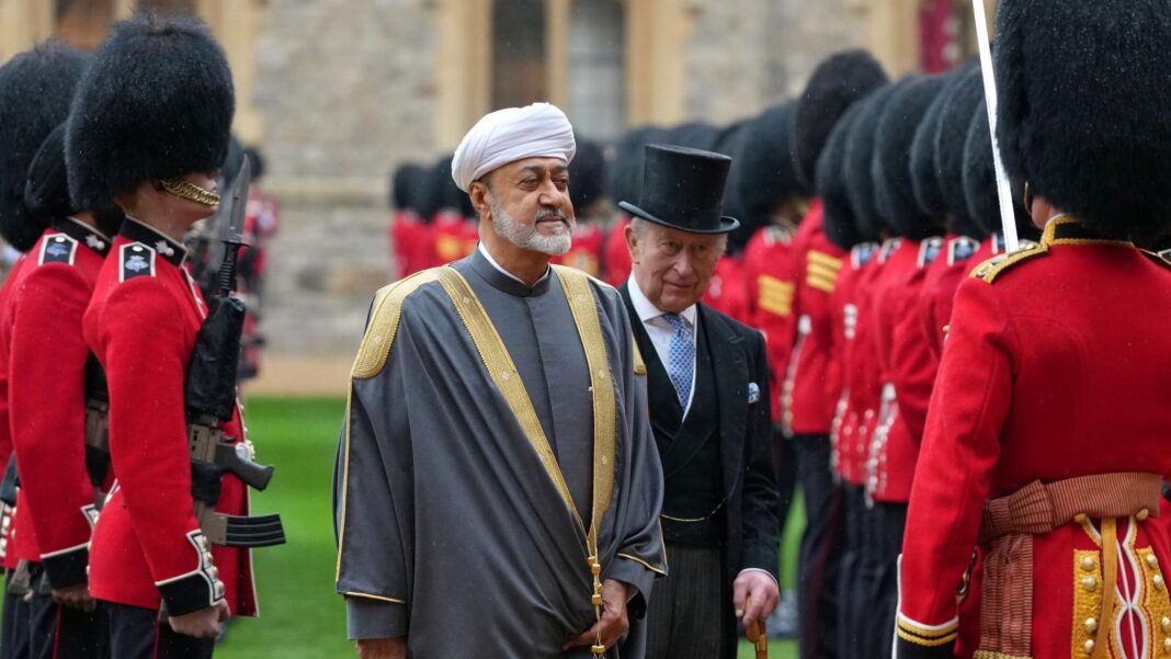 The Sultan of Oman standing in the foreground, with King Charles - in a top hat and three-piece suit - standing behind him, outside Windsor Castle