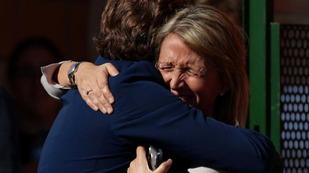 People embrace outside the municipal center where they have been taken