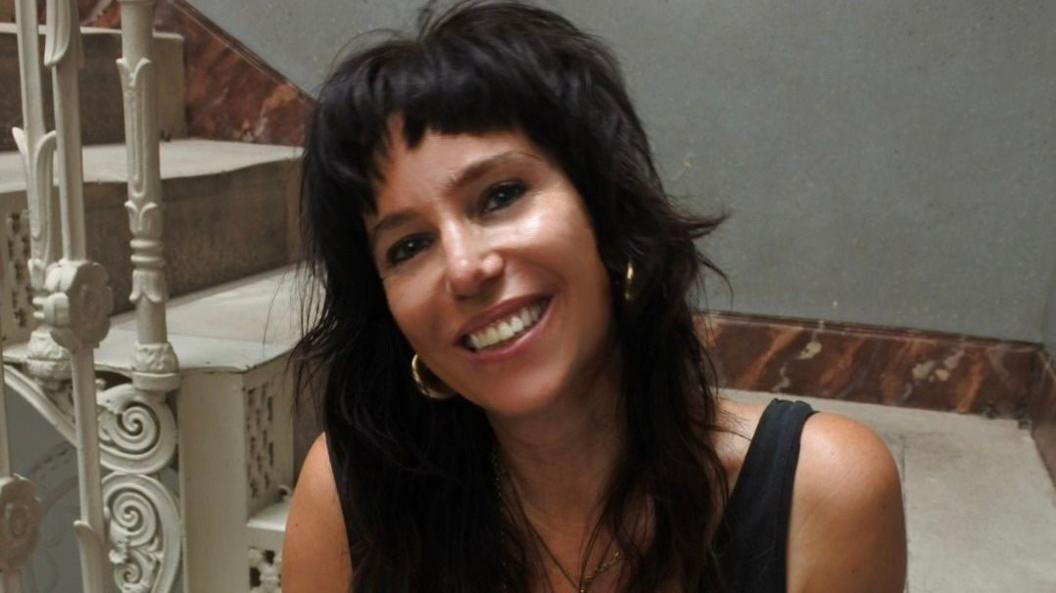 Jennifer Cox is sitting at the bottom of some white marble stairs and smiling at the camera.
