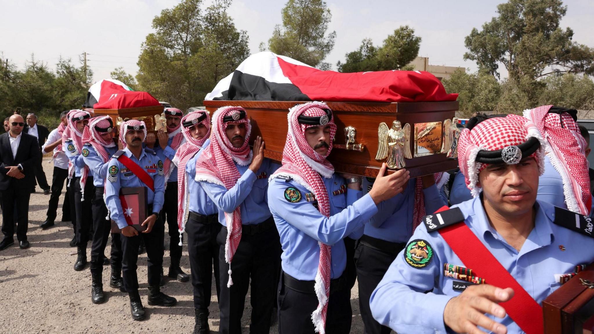 Jordanian security personnel carry the coffins of victims of a church shooting in Karak, Jordan (25 October 2026)