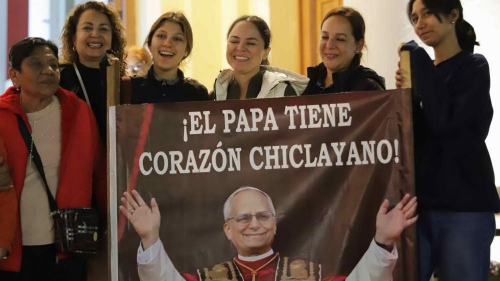 A group of women hold up a banner that depicts the Pope and bears the message (in Spanish): "Pope has Chiclayo's Heart"