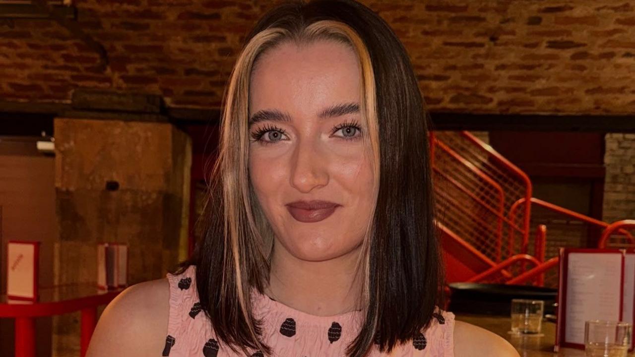 A close-up of Rachael Ellen. She has dark brown hair with blonde highlights and is smiling at the camera, wearing a pink and black polkadot top.
