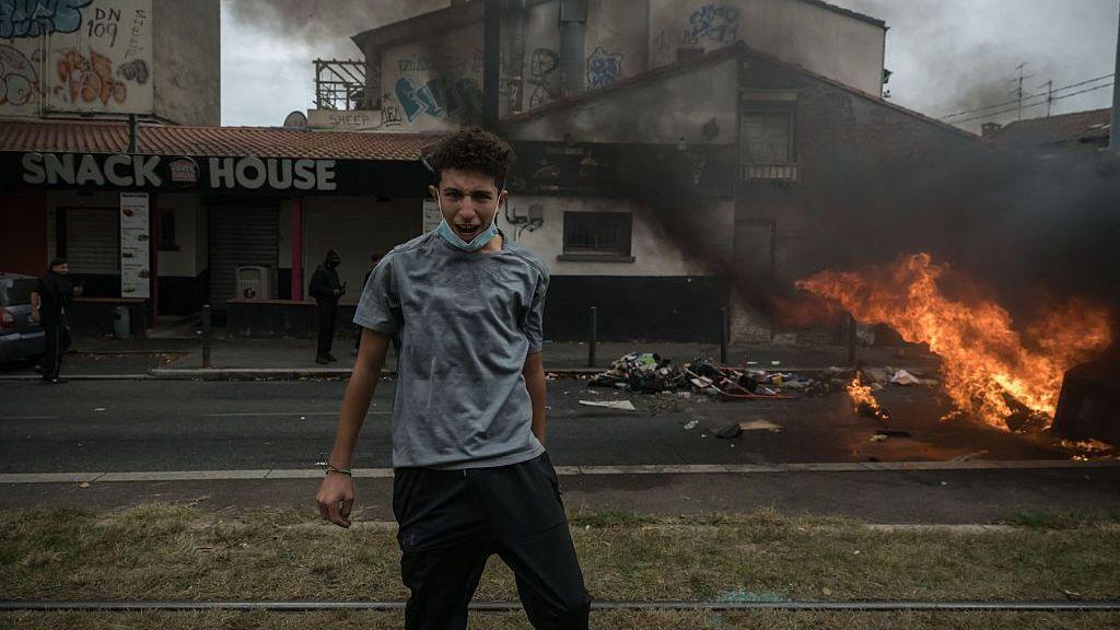 A student shouts while standing next to a burning barricade in Toulouse.
