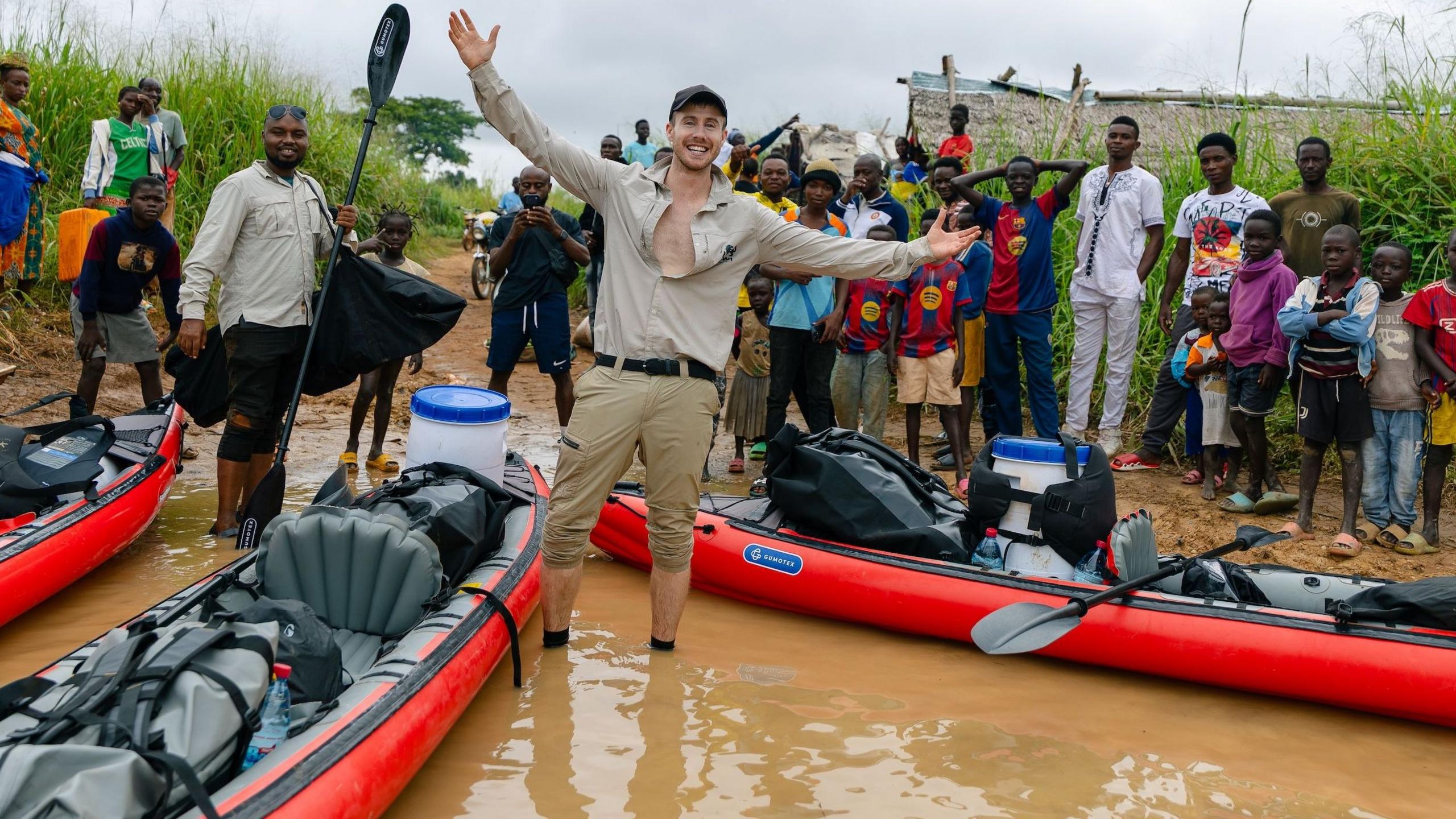 Ash Dykes standing by his kayak at the start of his journey with a line of local people waiting to wave him off