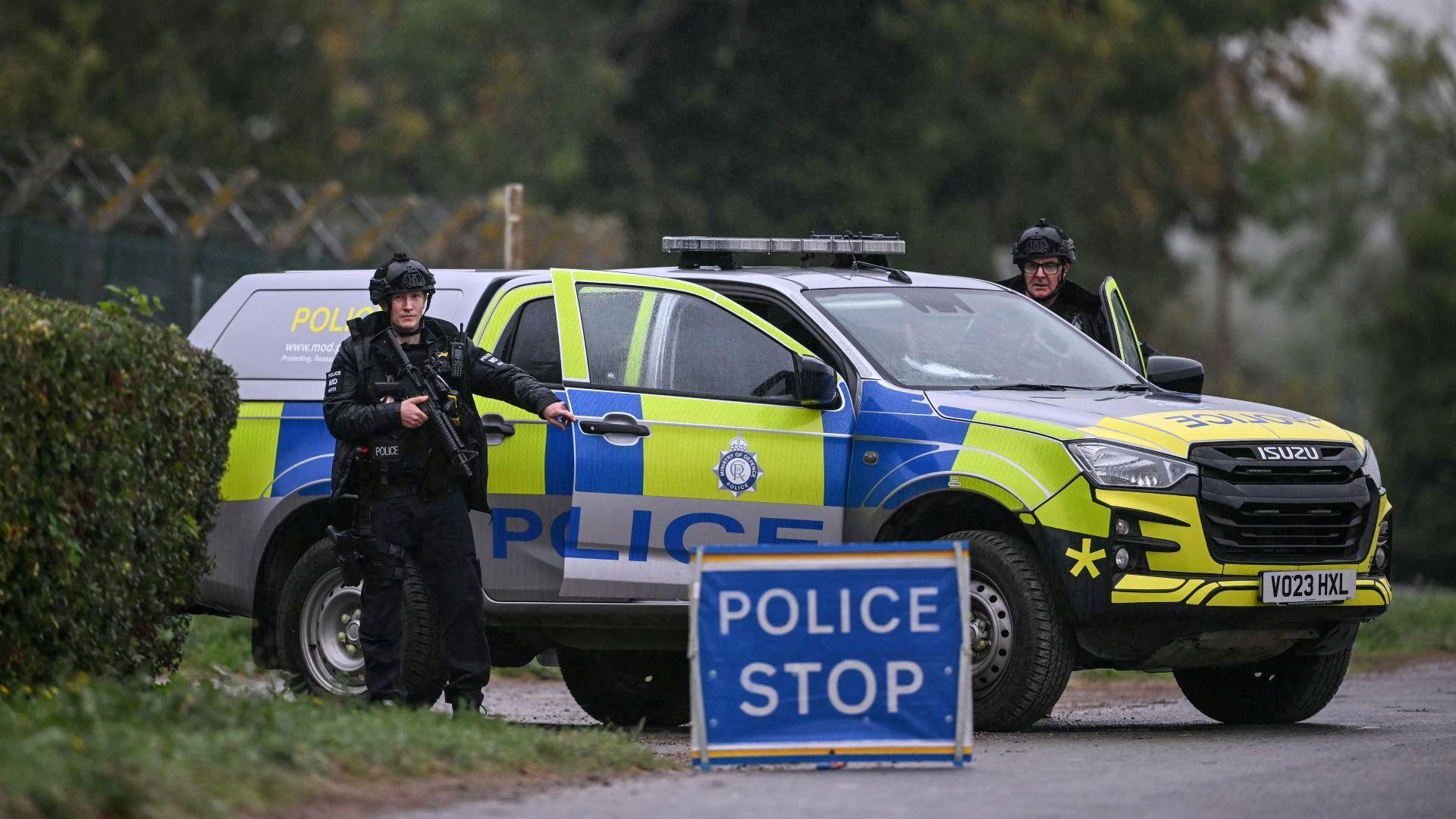 Two armed police officers posted outside RAF Fairford base on September 27. There is a police car, a police stop sign and two officers looking straight ahead