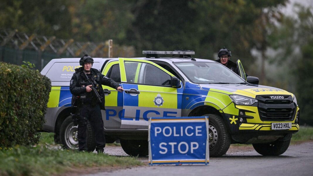 Two armed police officers posted outside RAF Fairford base on September 27. There is a police car, a police stop sign and two officers looking straight ahead