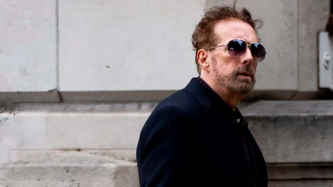 ‘Cult’ priest guilty of rape and assault of women A bearded man wearing a blue jacket and sunglasses walks past a building.